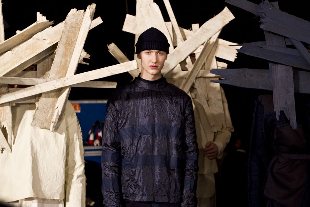 Model in dark outfit, black beanie, avant-garde London fashion.