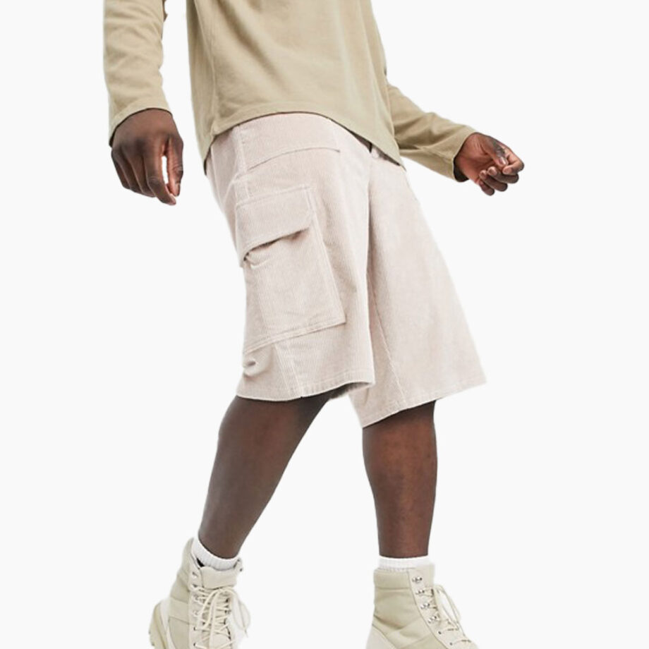 Man wears cargo shorts, beige shirt, cream boots.
