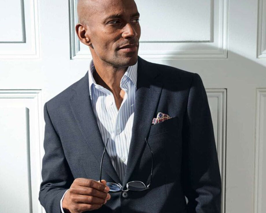 Man in dark suit, glasses, looks sophisticated.