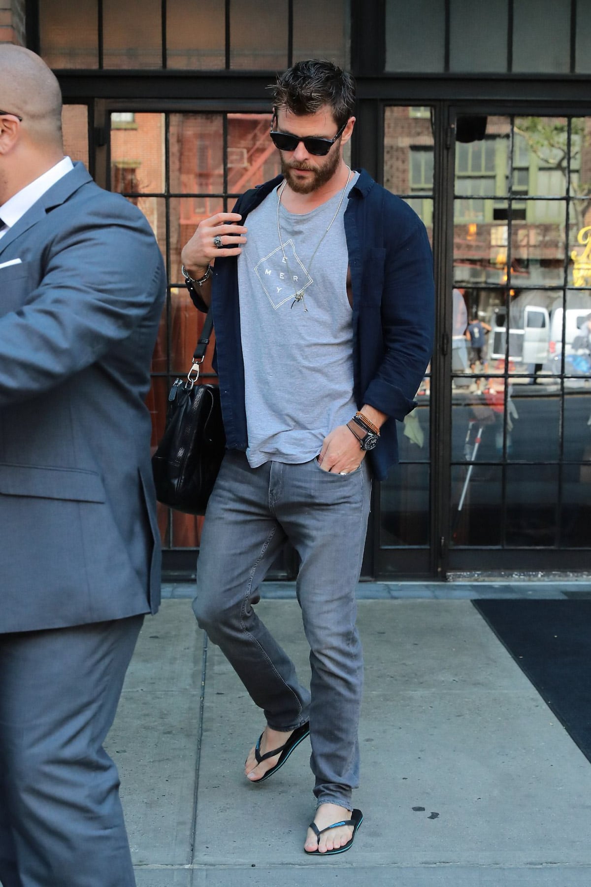 Bearded Hemsworth-lookalike strolls, suited bystander.