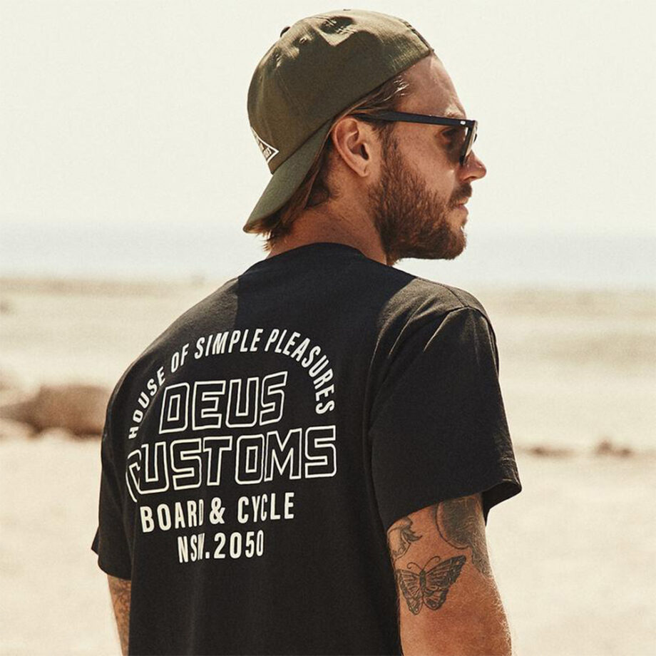 Man in Deus Customs shirt, shades, green cap.