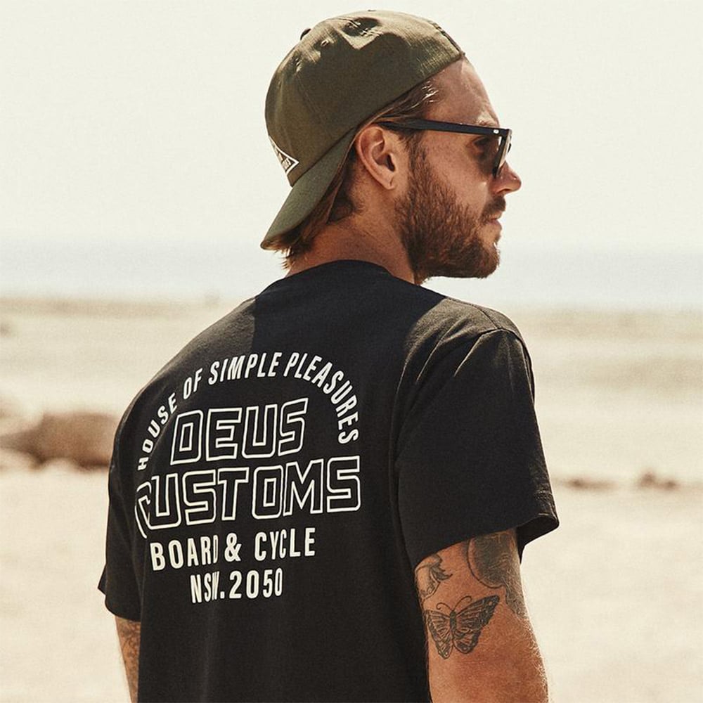 Man in Deus Customs shirt, shades, green cap.
