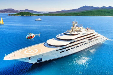 Helicopter over superyacht amidst scenic waters.