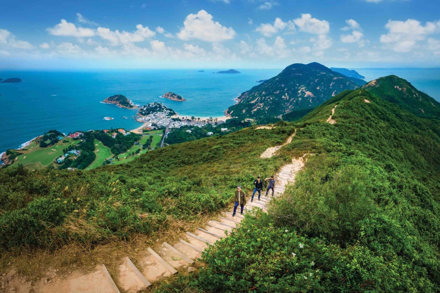 Hikers on Dragon’s Back trail overlooking Shek O and Tai Tam Bay.
