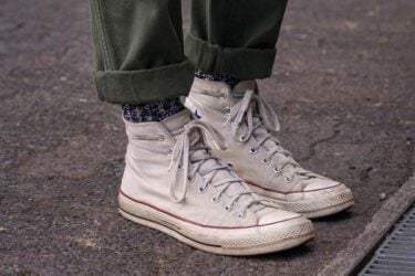 Person wears white Converse high-tops with style.