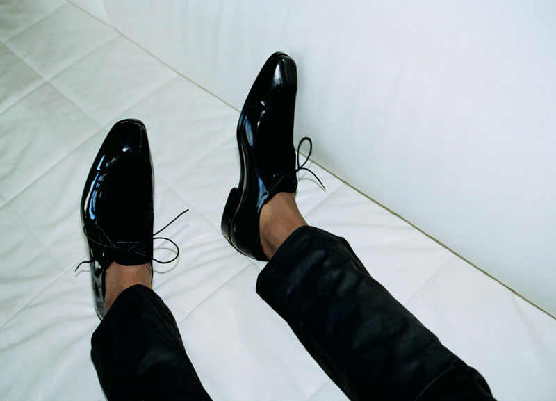 London-style: black pants, shiny dress shoes on white background.