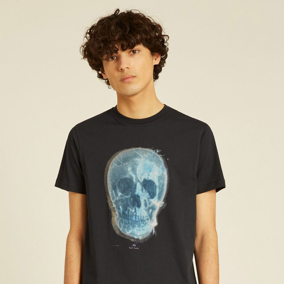 Curly-haired person wears black skull t-shirt.