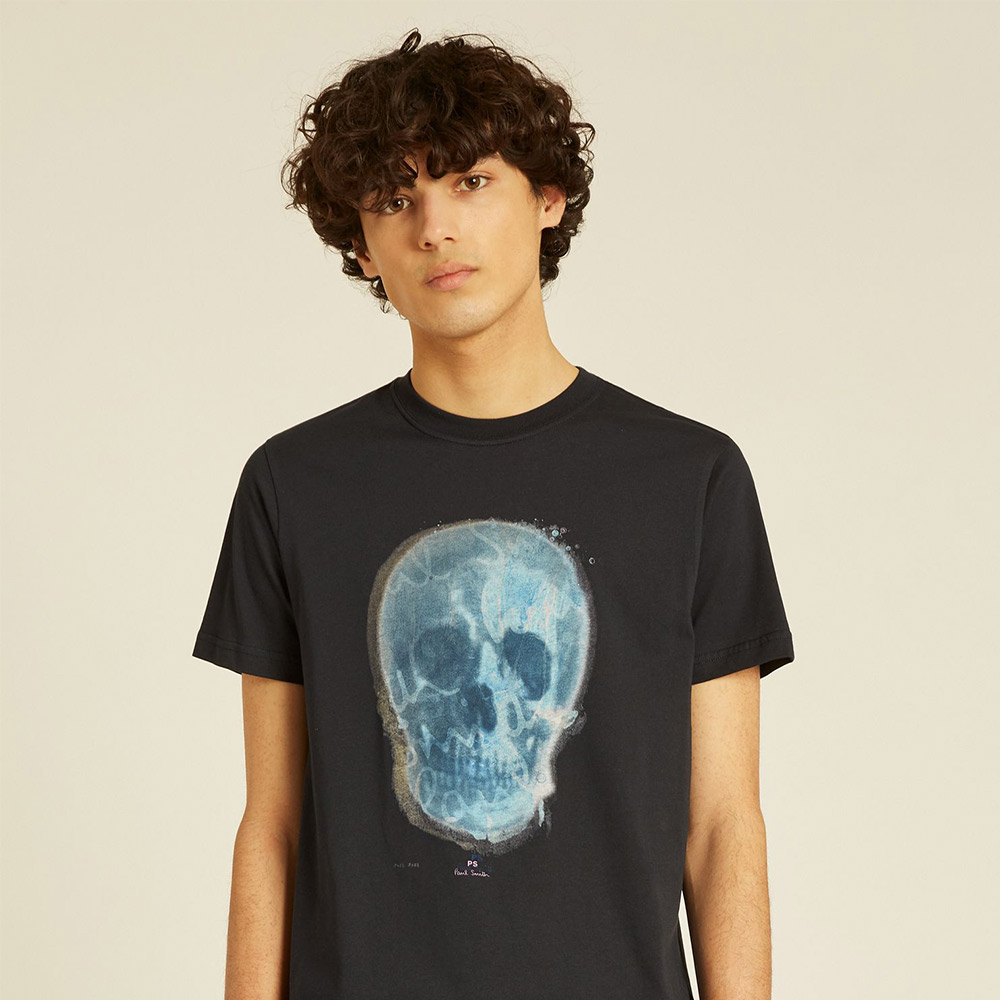Curly-haired person wears black skull t-shirt.
