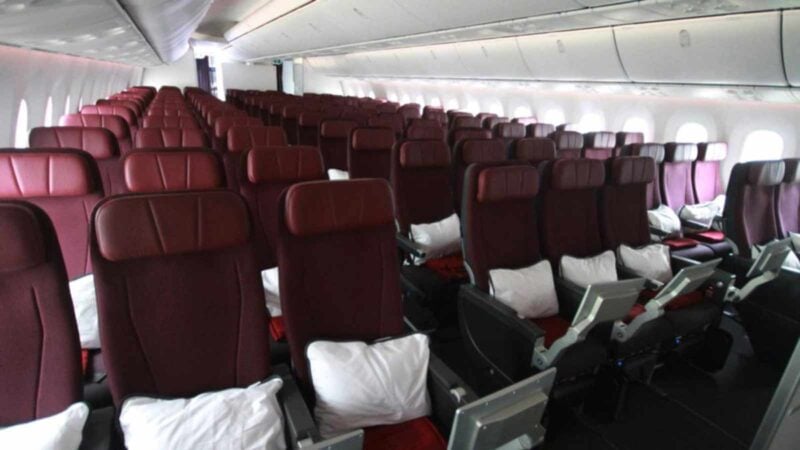 Qantas 787 cabin shows maroon seats, brightly lit.