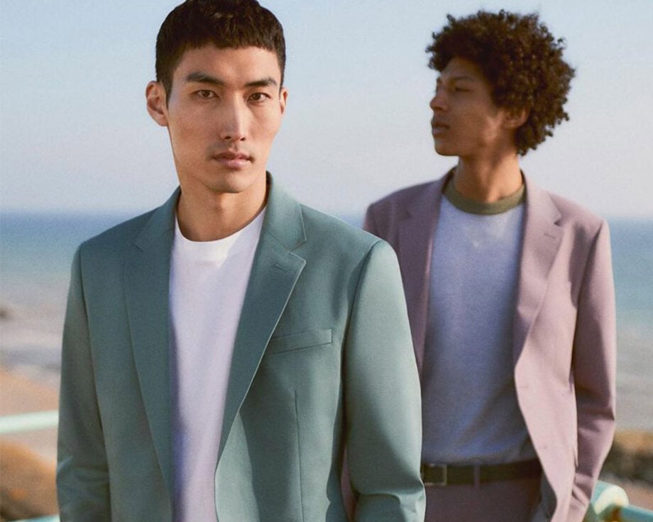 Men in suits with serene seaside backdrop.