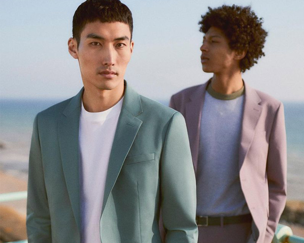 Men in suits with serene seaside backdrop.