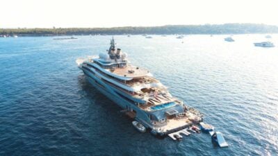 Luxurious superyacht anchored, features pool, multiple decks.