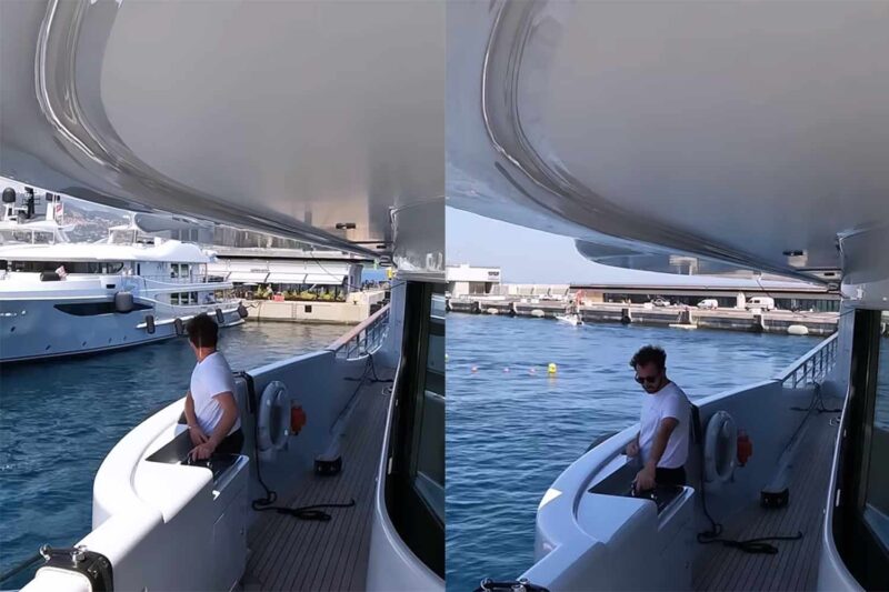 Man expertly navigates yacht near marina entrance.