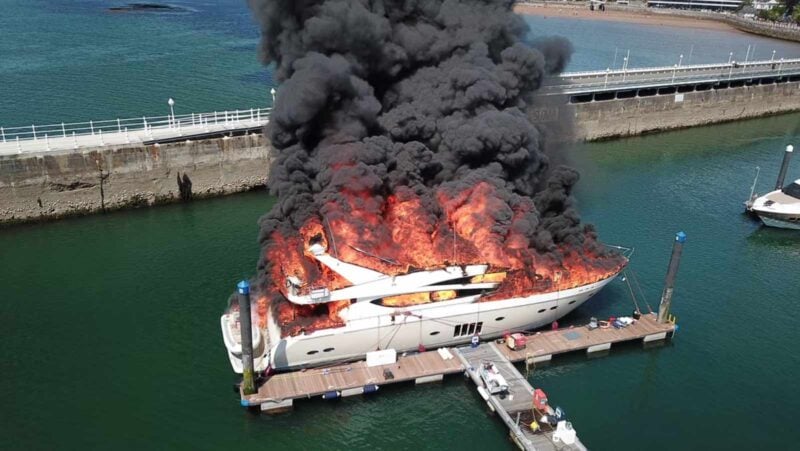 Superyacht on fire, emitting thick smoke.