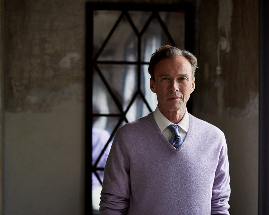 Man in lavender sweater with geometric mirror backdrop.